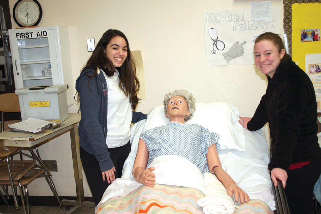 A PATIENT PATIENT: Alyssa Bailey and Brittany McSparren pose with one of the manequins used in the Medical Pathways program where students are taught proper techniques for handling patients during medical procedures.