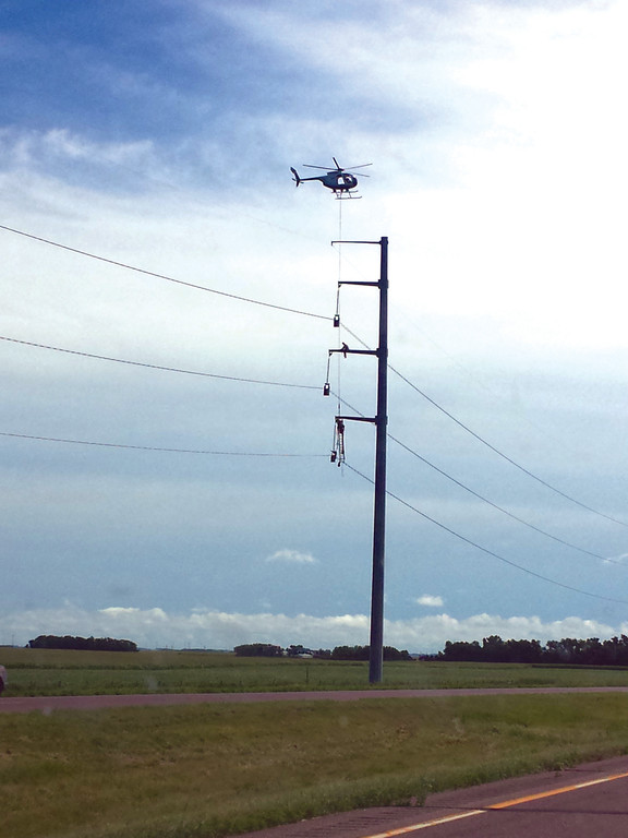 THE THINGS YOU SEE: We were continually fascinated by random crazy things we saw on this trip, such as this utility pole worker, lowered down to the middle of the pole by helicopter, where he sat and did his work as we drove by.