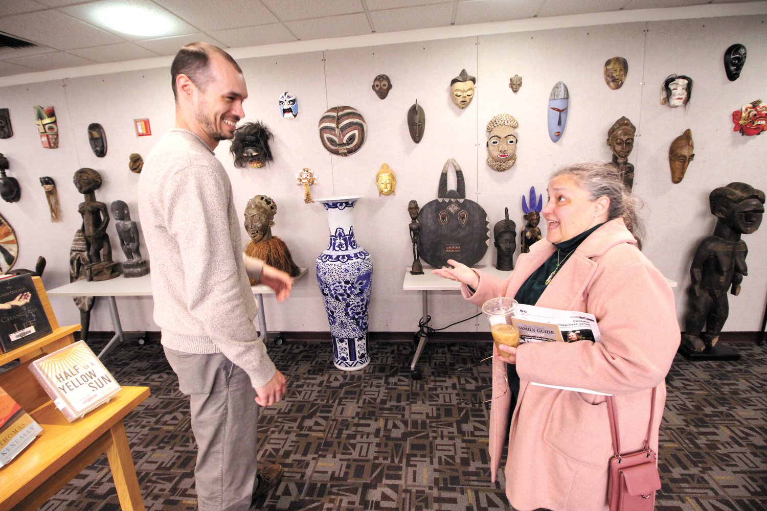 COMPARING NOTES: Justin Bibee talks with Mary Tramonti who stopped to look at the display of masks and figurines on display at the Warwick Public Library. Tramonti, who lived in Ethiopia, compared notes on living in Africa.